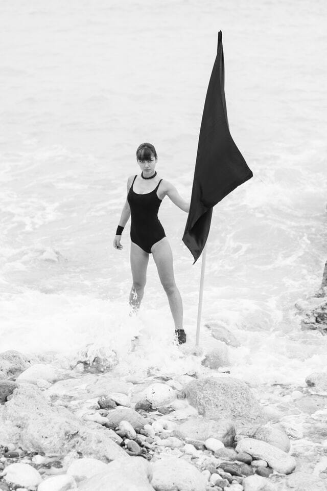 photo d'une femme sur la plage tenant un drapeau noir